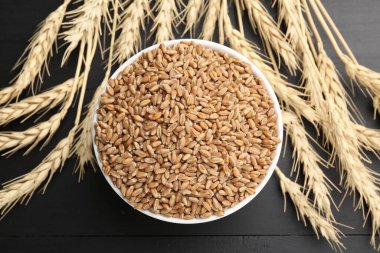 Kasede buğday taneleri ve siyah tahta masada çiviler, düz uzanmış.