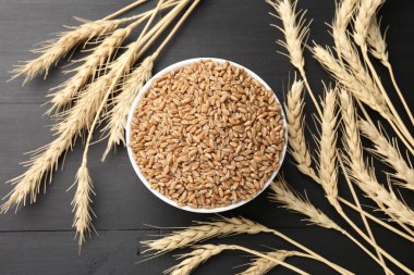 Kasede buğday taneleri ve siyah tahta masada çiviler, düz uzanmış.