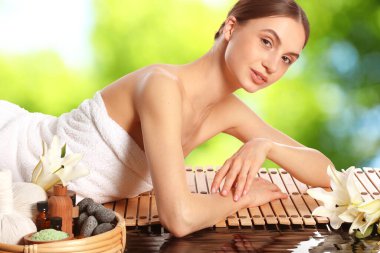 Bulanık yeşil arka planda bambu hasırında dinlenen güzel bir kadın. Spa merkezi