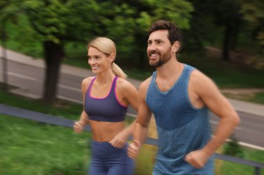 Spor giyimli erkek ve kadın açık havada koşuyor, hareket mavisi etkisi.