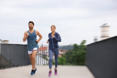 Spor giyimli erkek ve kadın açık havada koşuyor, hareket mavisi etkisi.