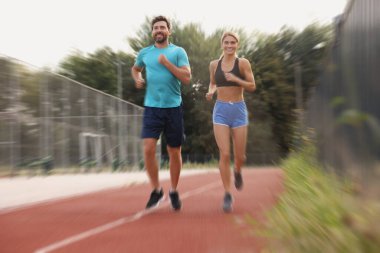 Spor giyimli erkek ve kadın açık havada koşuyor, hareket mavisi etkisi.