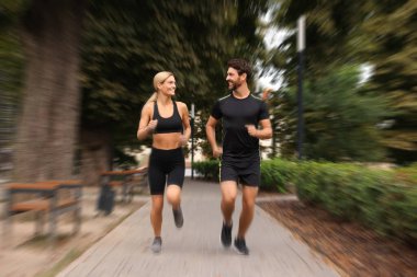 Spor giyimli erkek ve kadın açık havada koşuyor, hareket mavisi etkisi.