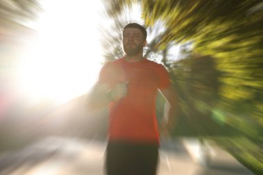Güneşli bir günde dışarı koşan atletik bir adam, hareket bulanıklığı etkisi