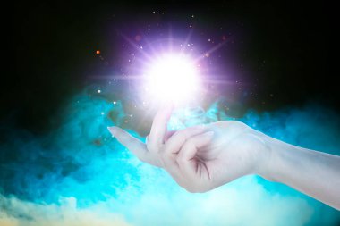 Siyah arka planda parlak bir ışık yaratan kadın, yakın plan. Aura, ruhani uygulama.