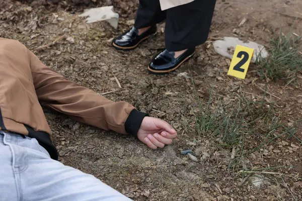 Adli tıp uzmanlığı. Dedektif, olay yerindeki cesedin yanında, dışarıda, yakın mesafede.