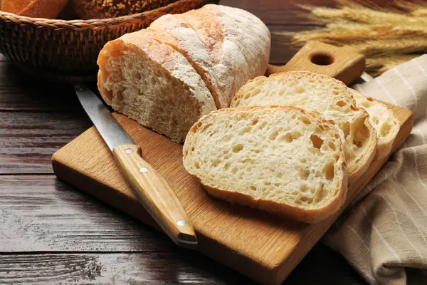 Taze ekmek, bıçak ve buğday çivileri ahşap masada, yakın plan.