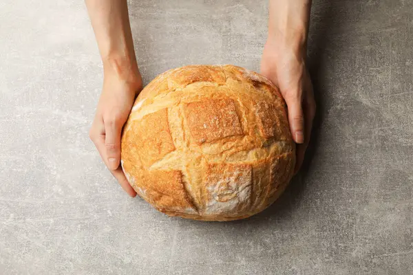 Gri masada bir somun taze ekmeği olan kadın.