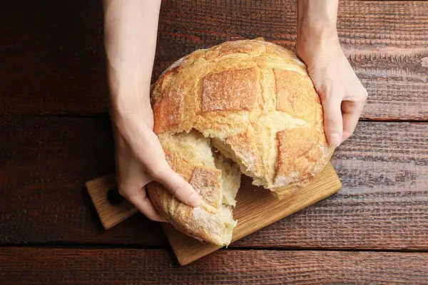 Ahşap masada taze ekmek paylaşan bir kadın.