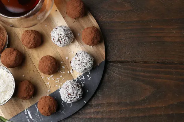 Ev yapımı lezzetli şekerler kakao tozu, hindistan cevizi gevreği ve ahşap masada çay, düz yatak. Metin için boşluk