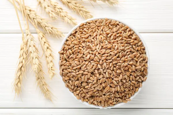 Kasede buğday taneleri, beyaz tahta masada çiviler, düz uzanmış.