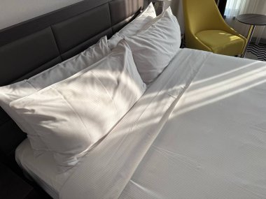 Otel odasında yumuşak yastıkları ve koltuğu olan rahat bir yatak.