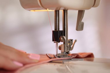 Atölyede dikiş makinesi ve kumaşla çalışan bir kadın.