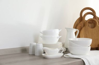 Mutfaktaki tezgahta farklı beyaz bulaşık takımları ve tahta kesme tahtaları var.