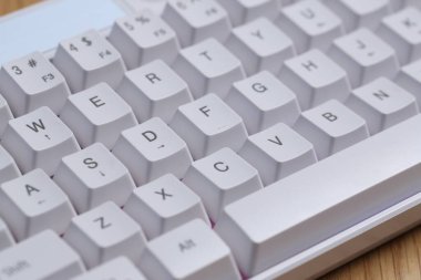 Ahşap masa üzerinde RGB ışıklandırmalı modern beyaz klavye, yakın plan