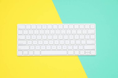 Renk arkaplanı üzerinde modern beyaz kablosuz klavye, üst görünüm