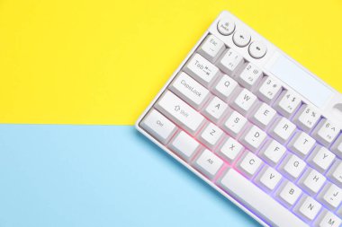 Renkli arka planda RGB ışıklandırması olan modern beyaz klavye, üst görünüm. Metin için boşluk