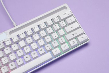 Menekşe arkaplan üzerinde RGB ışıklandırması olan beyaz klavye, üst görünüm