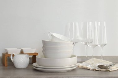 Mutfakta farklı beyaz bulaşık takımları, bardaklar ve çatal bıçaklar var.