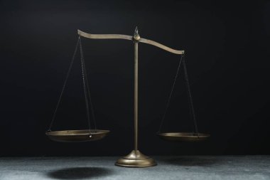 Gri masadaki adalet terazileri siyah arkaplan karşısında