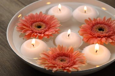 Mumları yakıyor, çiçekleri suyla dolduruyor, ahşap masada, yakın plan.