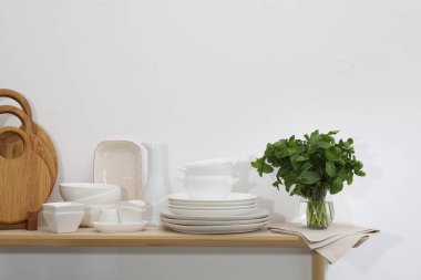 Temiz bulaşık takımları, tahta kesme tahtaları ve beyaz duvarın yanındaki tahta masada nane şekeri.