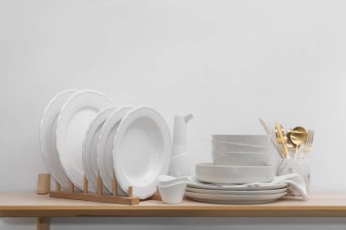 Beyaz duvarın yanındaki ahşap masada temiz bulaşık takımı. Metin için boşluk