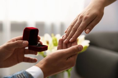 Nişan yüzüklü bir adam içeride kız arkadaşına evlenme teklif ediyor.