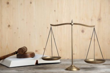 Adaletin altın pulları, tahta masa üzerinde tokmak ve kitap.