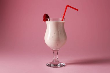 Nefis ahududu milkshake 'i pembe arka planda bardakta