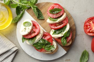 Mozarella peynirli, domatesli ve fesleğenli lezzetli sandviçler gri desenli masa, düz uzanış