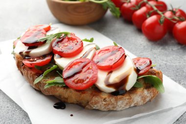 Mozarella peynirli lezzetli sandviç, balzamik sos, domates ve roka gri masada, yakın plan.