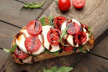 Mozarella peynirli lezzetli sandviç, balzamik sos, domates ve roka ahşap masa, üst manzara