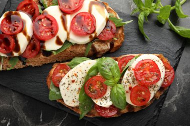 Mozarella peynirli lezzetli sandviçler ve siyah mermer masada domatesler.