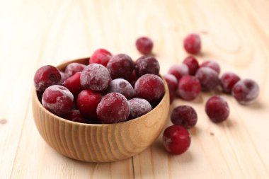 Olgun donmuş kirazlar ve kase açık ahşap masada, yakın plan.