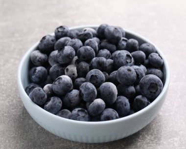 Olgun donmuş yaban mersinleri kasede Gri desenli masada, yakın plan