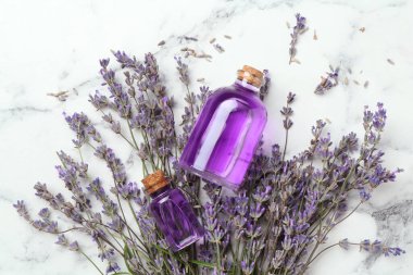 Beyaz mermer masanın üzerinde, şişelerde ve lavanta çiçeklerinde, yassı yağ.