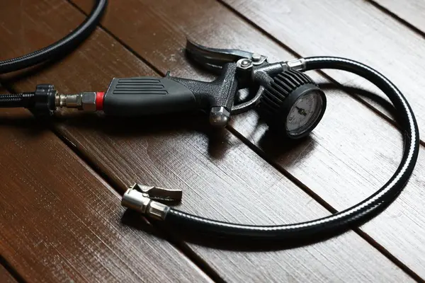 Ahşap arka planda göstergesi olan bir lastik enflasyon silahı, yakın plan.