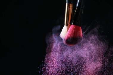 Siyah arka planda renkli göz gölgeli makyaj fırçaları, yakın plan. Metin için boşluk