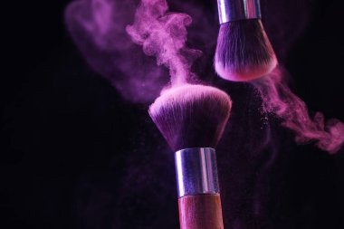 Renkli göz gölgeli makyaj fırçaları siyah arka planda neon ışıkları, yakın plan. Metin için boşluk