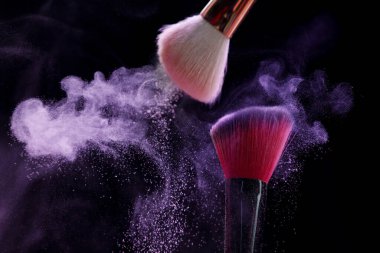 Siyah arka planda mor göz farlı makyaj fırçaları, yakın plan. Metin için boşluk