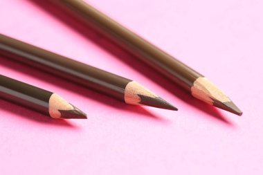 Pembe arka planda farklı kaş kalemleri, yakın plan.