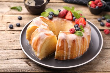 Lezzetli kek parçaları, böğürtlenli, jöleli ve naneli ahşap masa, yakın plan.