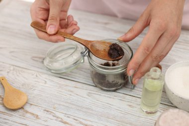 Beyaz ahşap masada doğal vücut ovuşturan kadın, yakın plan.