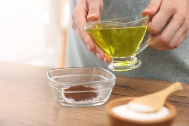 Doğal temizlik yapıyorum. Ahşap masada yağlı boya katan kadın, yakından.