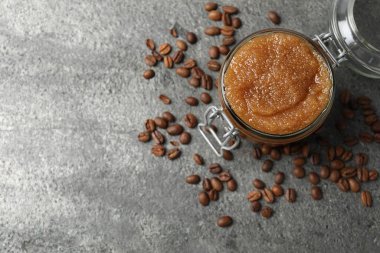 Doğal vücut fırçası cam kavanozda ve kahve çekirdekleri gri masada, düz yerde. Metin için boşluk