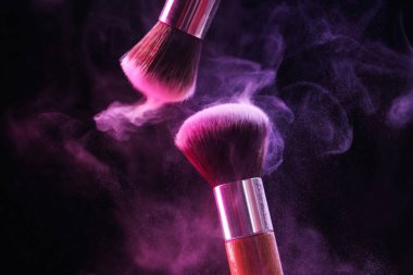 Renkli göz gölgeli makyaj fırçaları siyah arka planda neon ışıkları, yakın plan