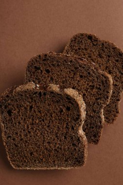 Kahverengi arka planda taze çavdar ekmeği parçaları.