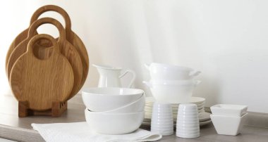 Mutfakta farklı beyaz bulaşık takımları ve tahta kesme tahtaları var.