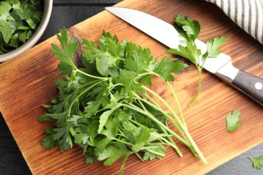 Taze aromalı maydanoz ve bıçak siyah ahşap masada, düz yatıyordu.